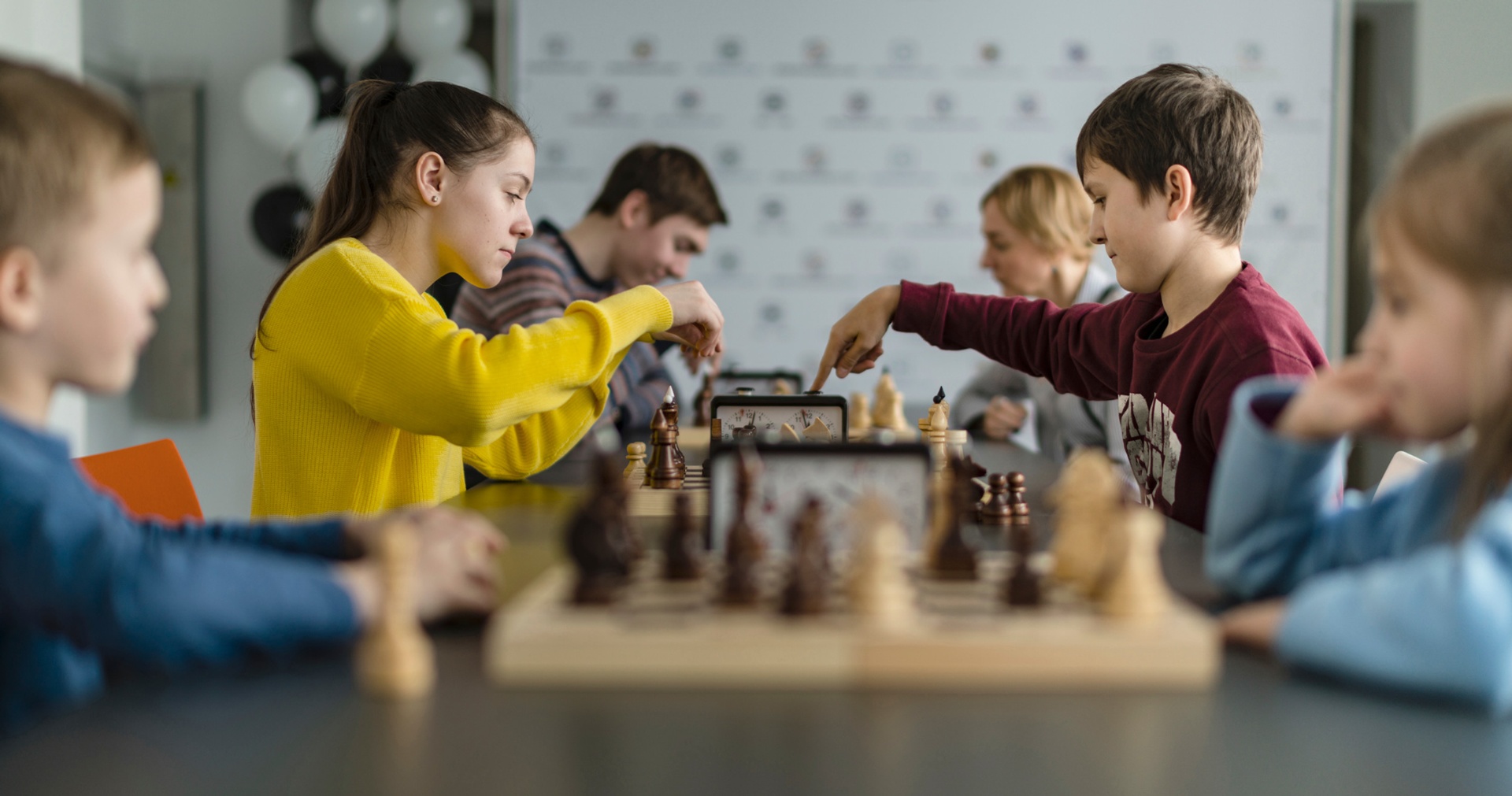 Two children focused on a serious chess game with a timer.